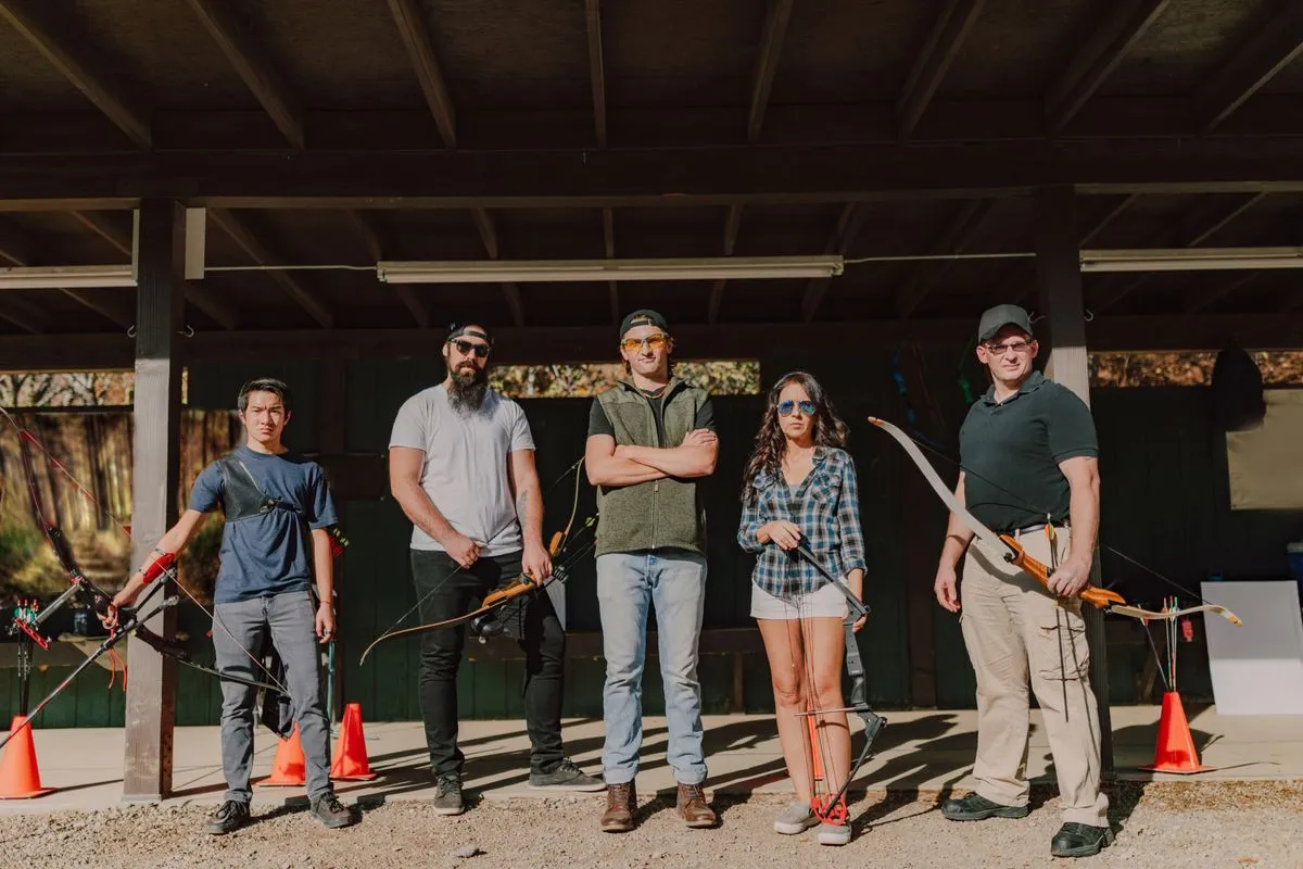 A group of five adults standing with bows at an outdoor range