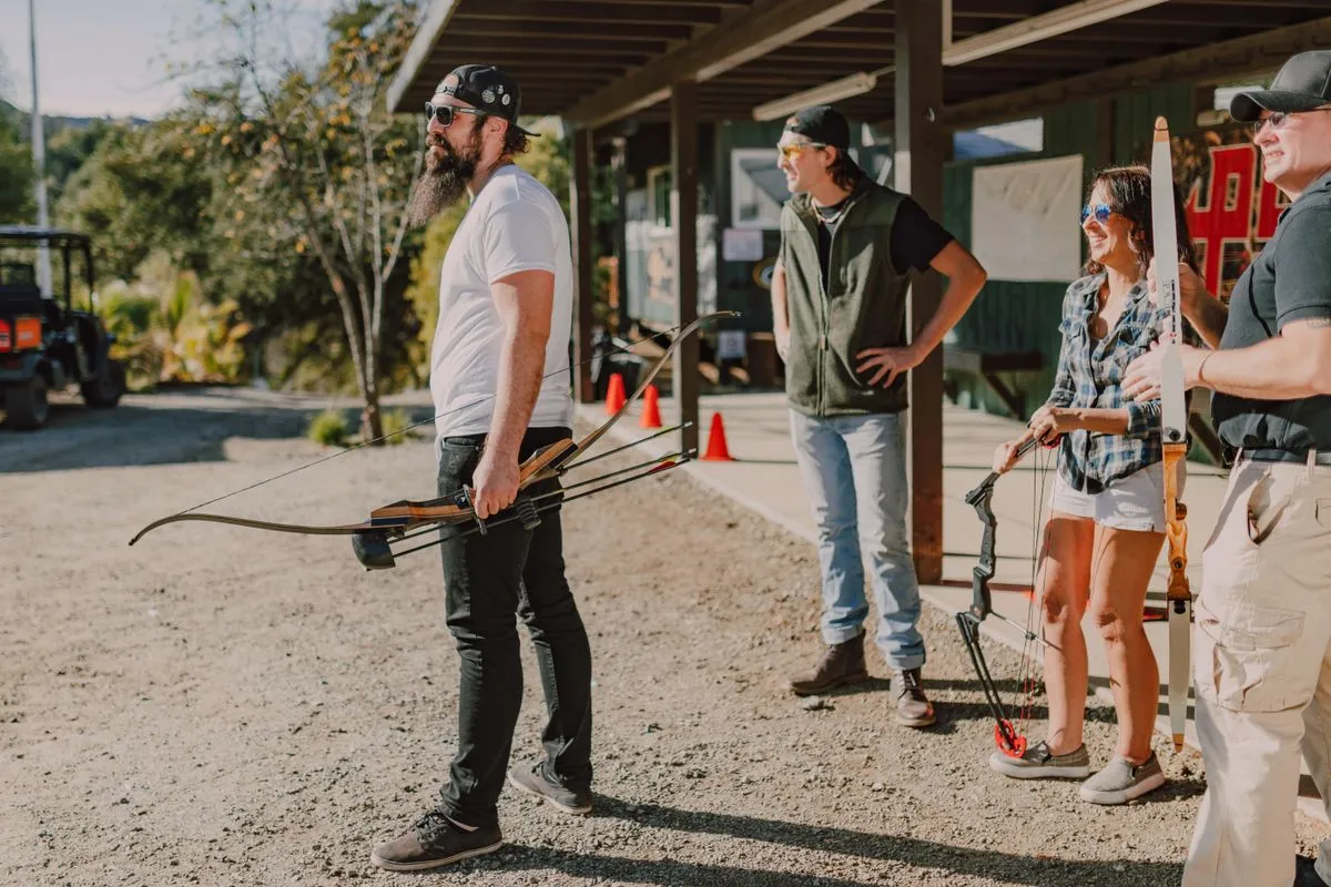 Adults with bows at a covered archery range