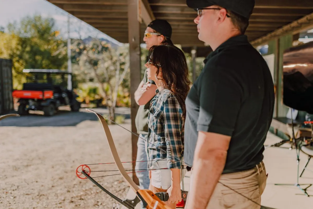 A group of adults learning archery at an outdoor range