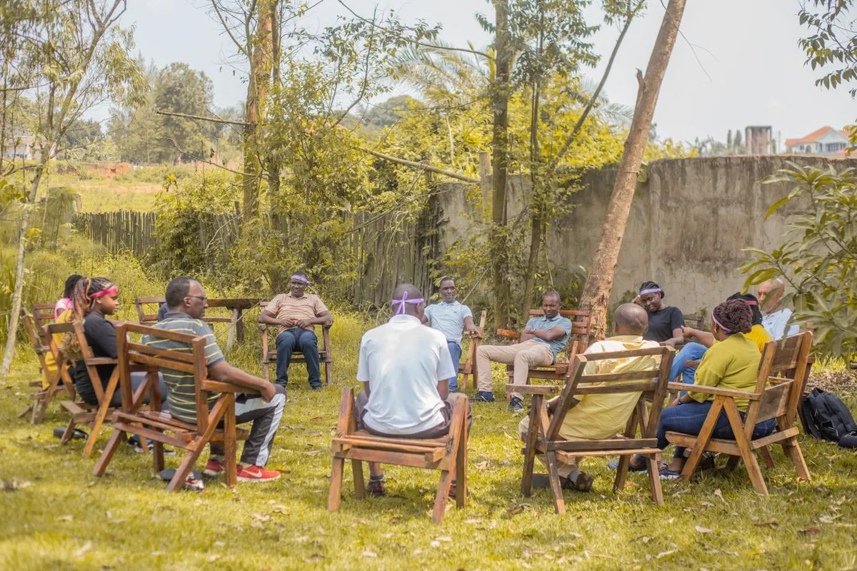 A group sitting in outdoor chairs talking in a clearing