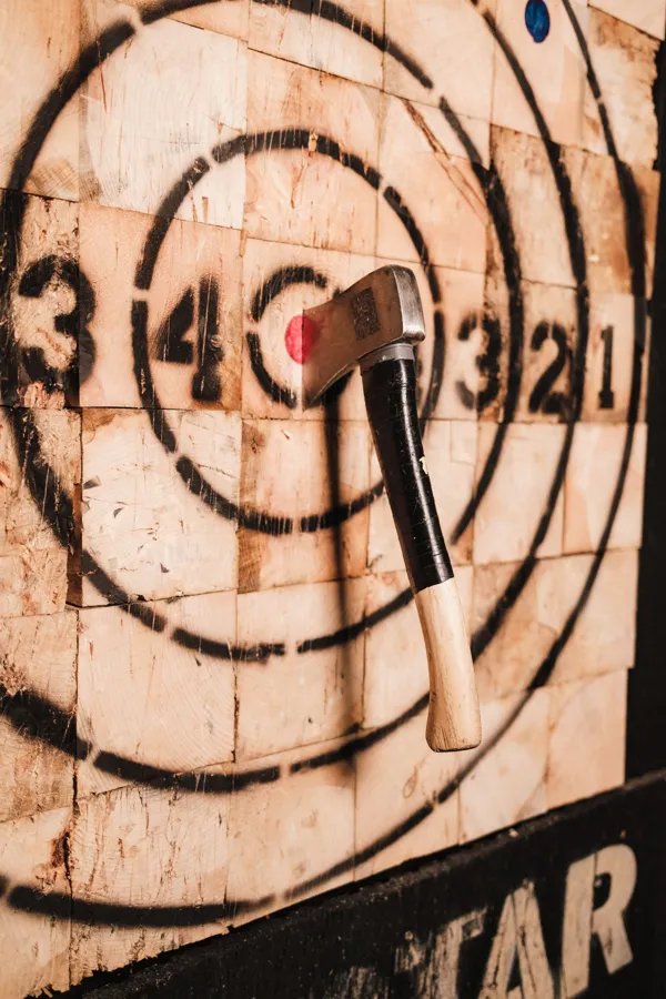 A dramatic close-up of an axe embedded in a wooden target.