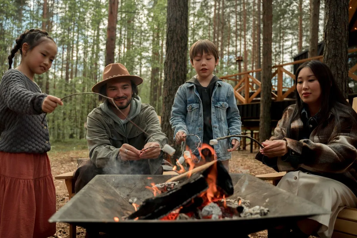 A family roasting marshmallows over a campfire in the woods
