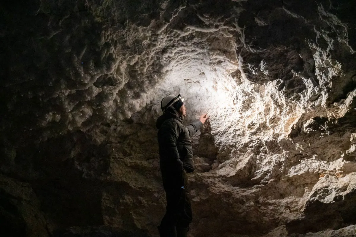A person explores a rocky cave using a headlamp.
