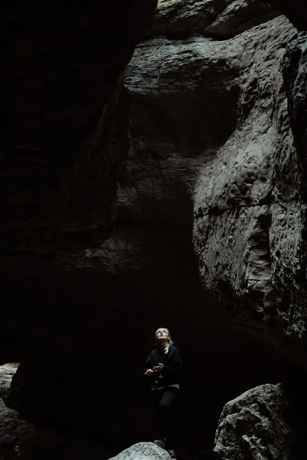 Woman exploring inside a rocky cave.