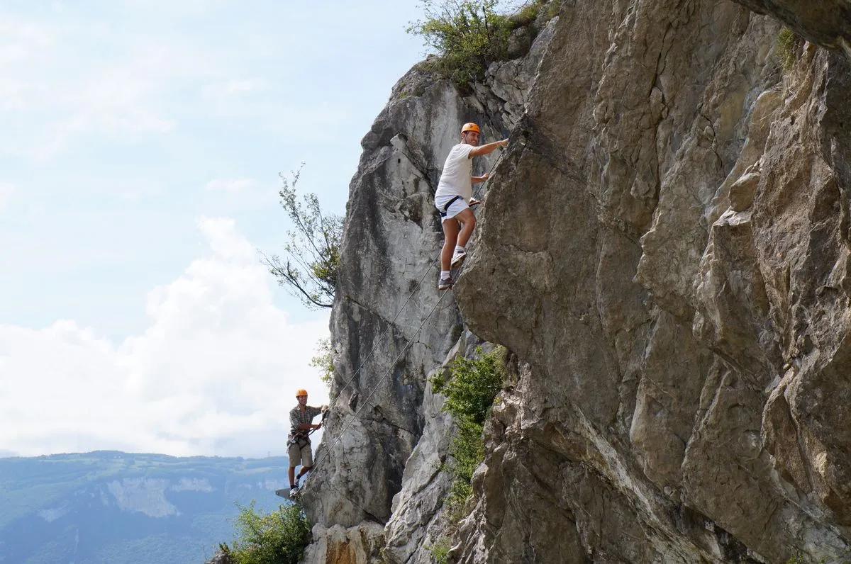 Two climbers ascend a rugged cliff.