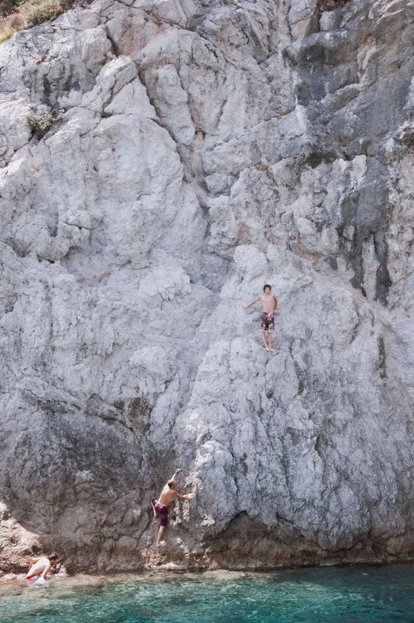 Thrill-seekers prepare to jump off rocky cliffs into turquoise waters in Marmaris, Türkiye.