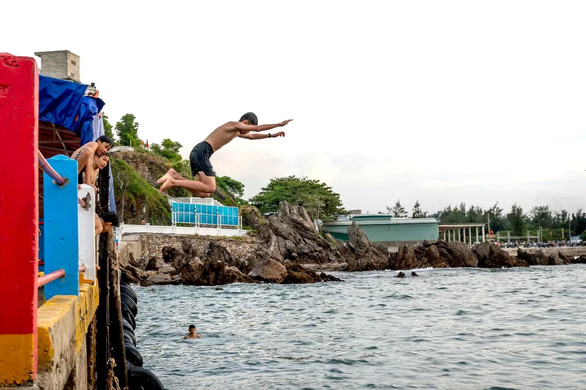 Teenagers leaping into the sea from a colourful pier