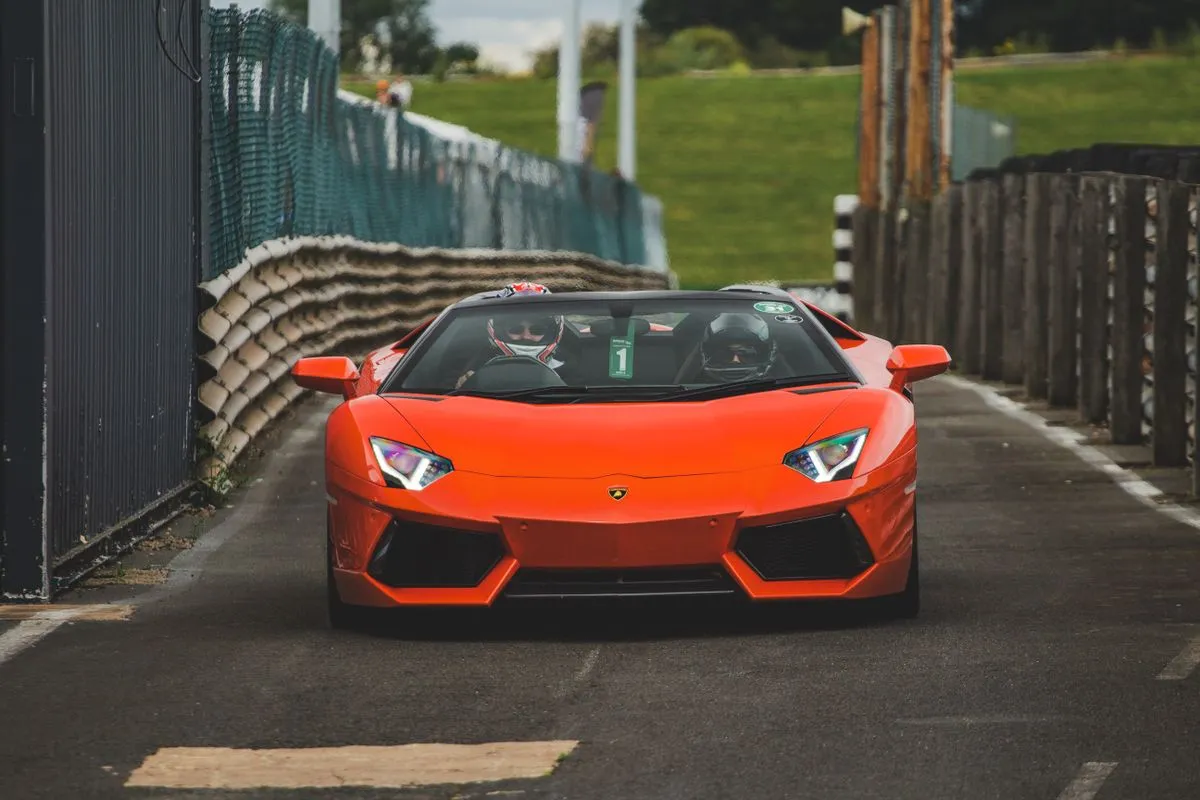An orange sports car driving down a closed track.