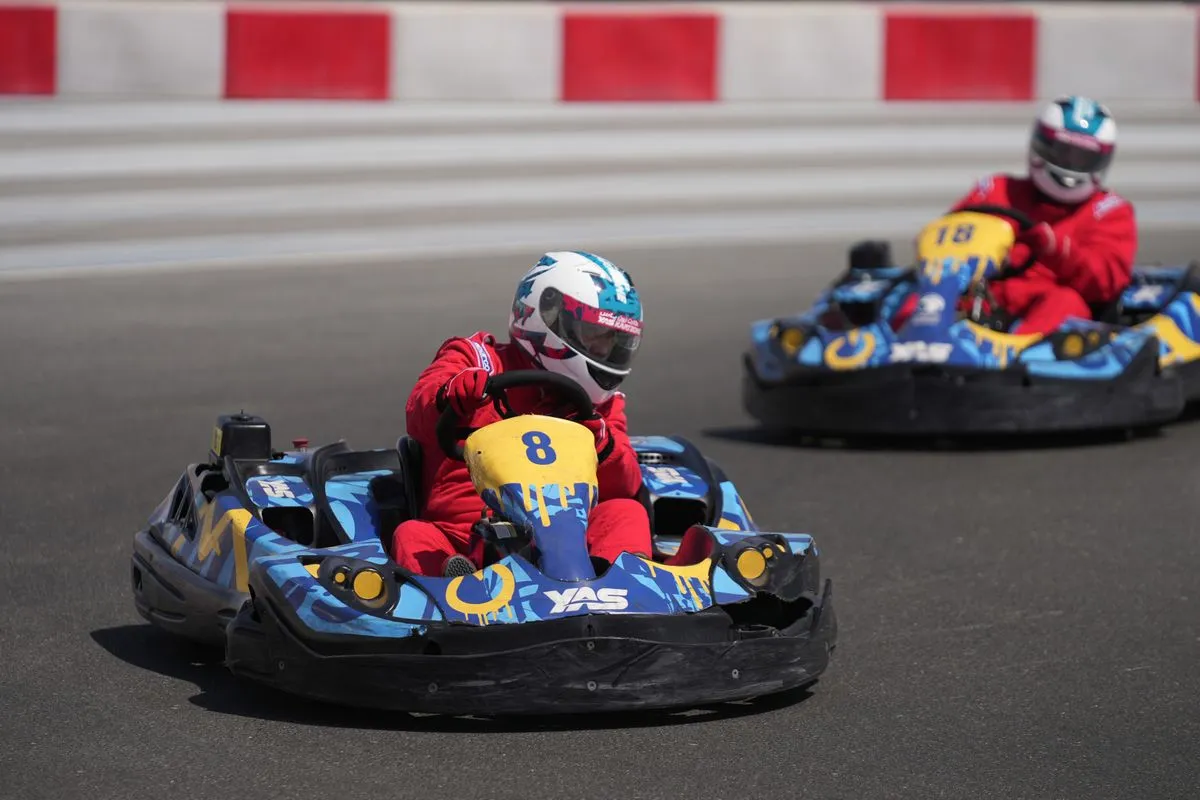 Two drivers in helmets racing go-karts on an outdoor track.