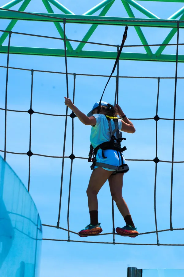 A climber on a net wall in front of a bright blue sky
