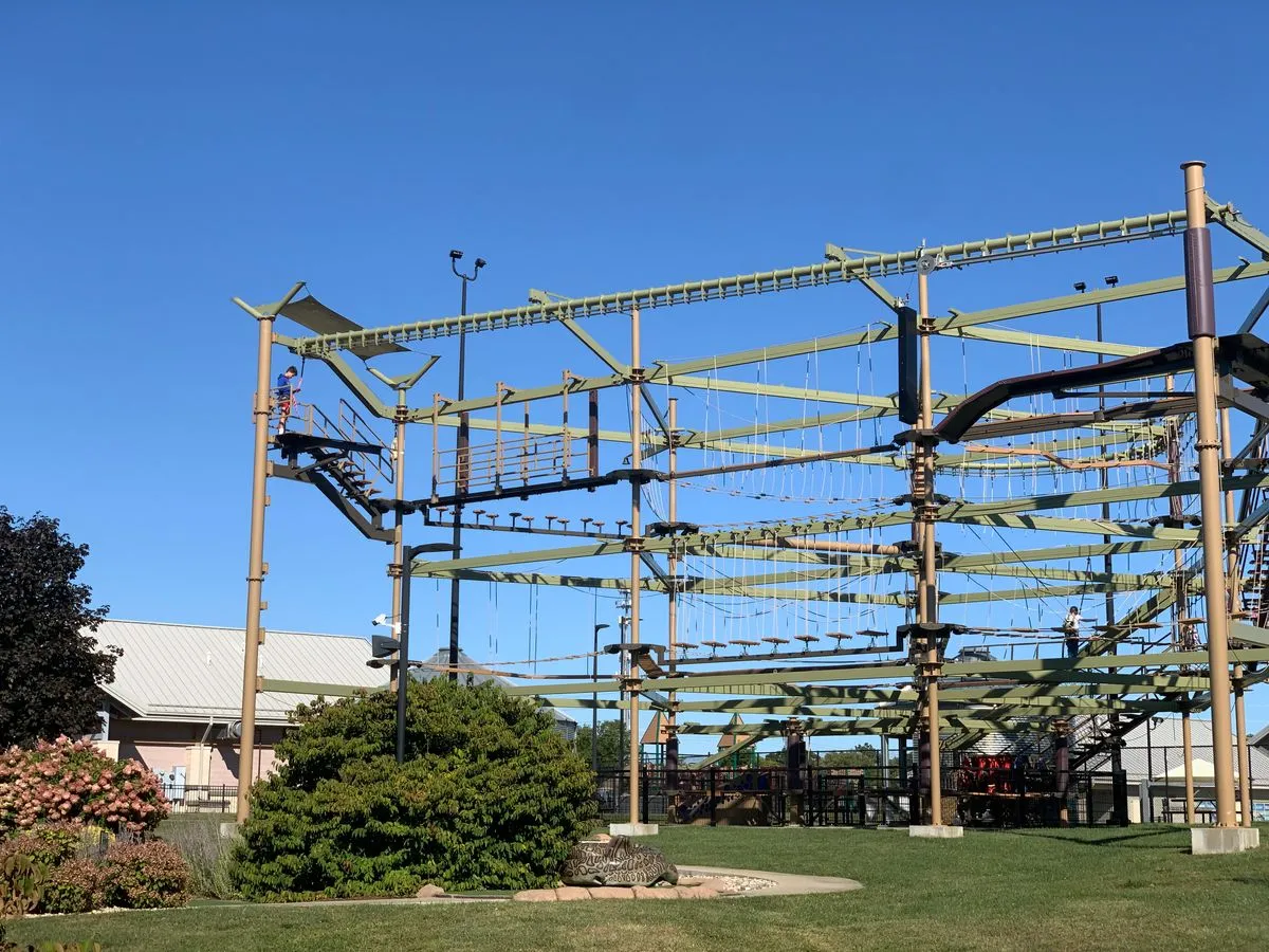 A multi level ropes course frame under a clear blue sky