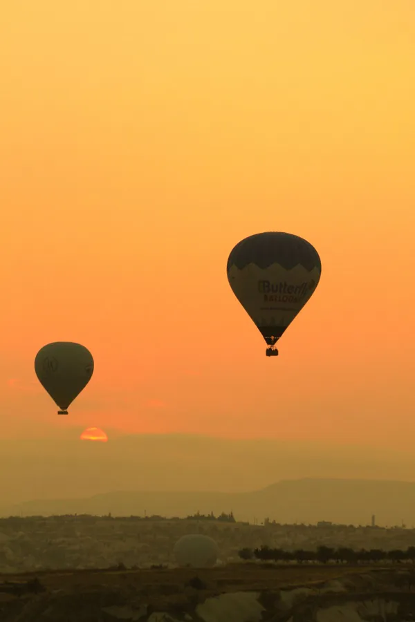 Scenic view of hot air balloons over Cappadocia at sunset.