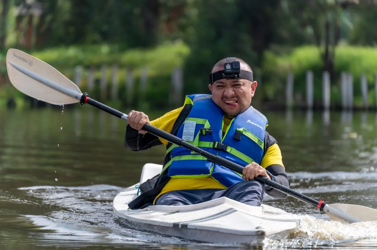 A kayaker in a buoyancy aid and helmet paddling on calm water