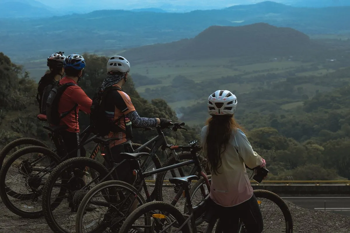 A group of cyclists stopping at a viewpoint over green hills