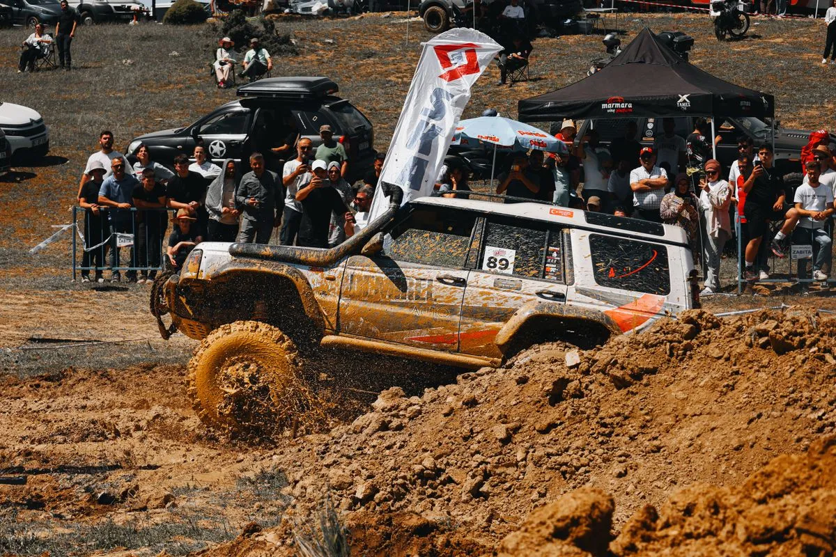 A thrilling moment in an off-road car race with spectators and flying mud.