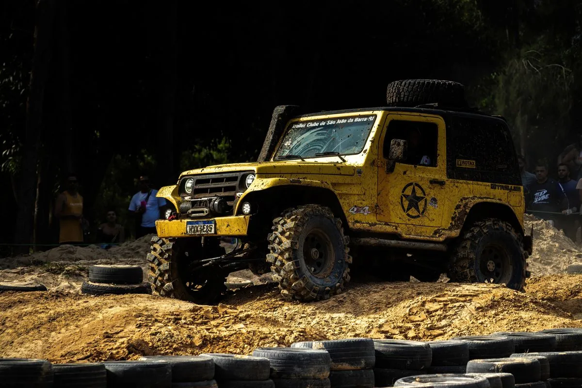 A yellow off-road vehicle crossing rough, muddy ground.