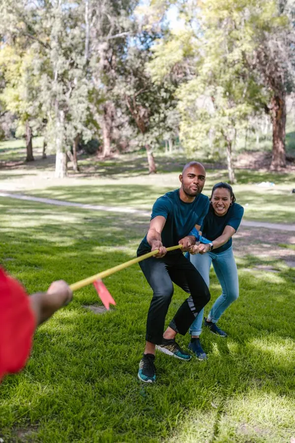 A group playing tug of war in a park