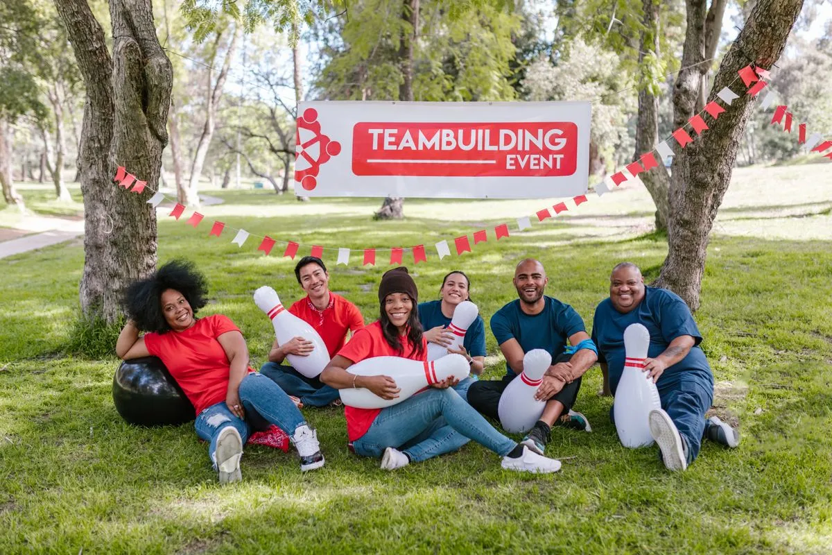 A joyful group participates in a team building event outdoors with bowling pins.