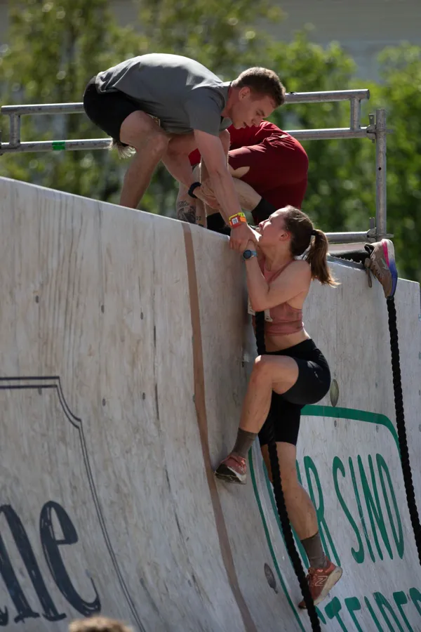 Participants working together to overcome an obstacle in an outdoor race.