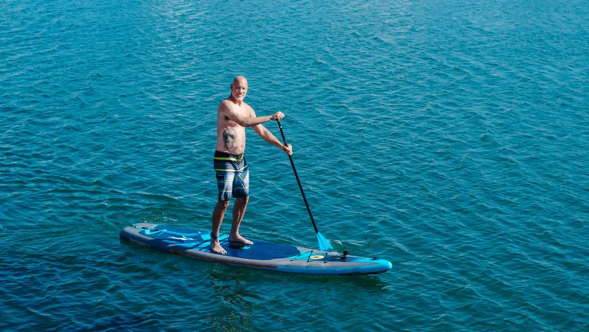 A man paddle boarding on calm blue water.