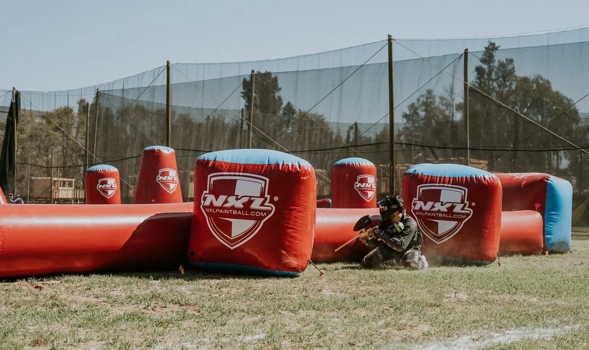 Player in action during a competitive paintball game outdoors.