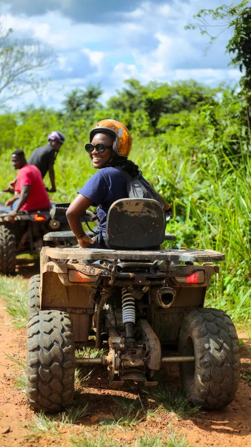 Riders on muddy quad bikes on a green forest track