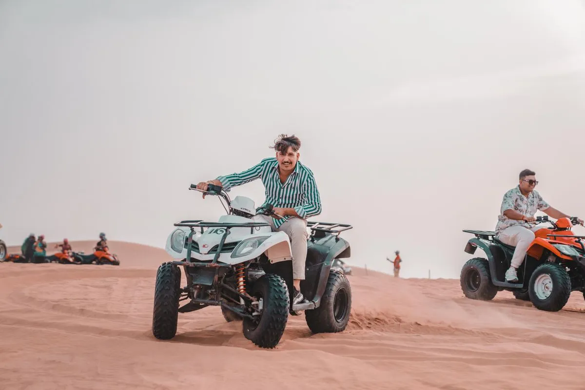 Two riders on quad bikes on pink sand dunes