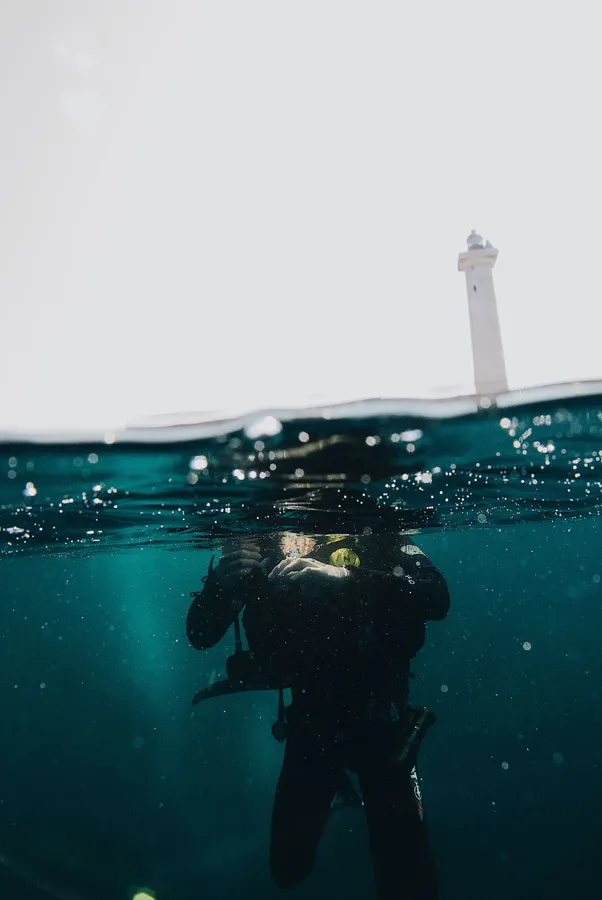 A scuba diver surfacing near a lighthouse