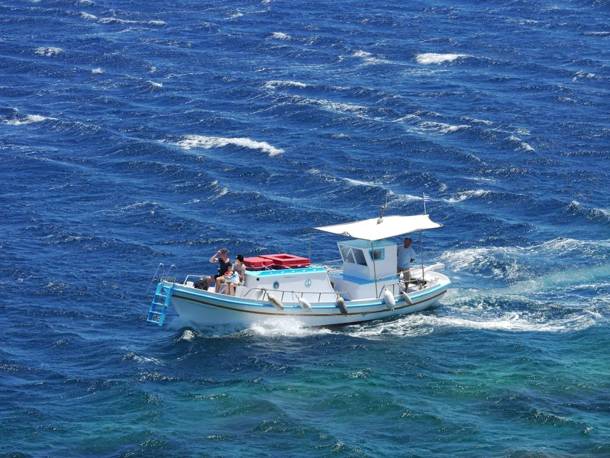 A small boat on bright blue open water seen from the air