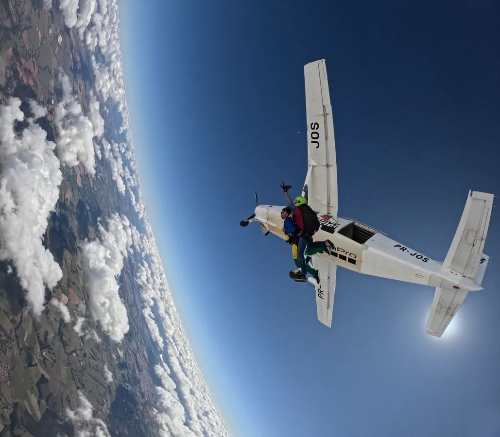 Exciting tandem skydiving jump from aircraft, high above scenic scenery.