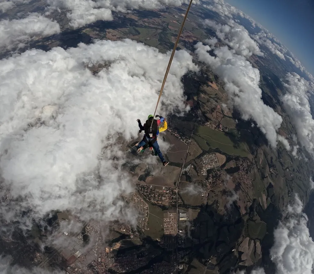 Tandem skydivers bravely descend through clouds with a parachute.