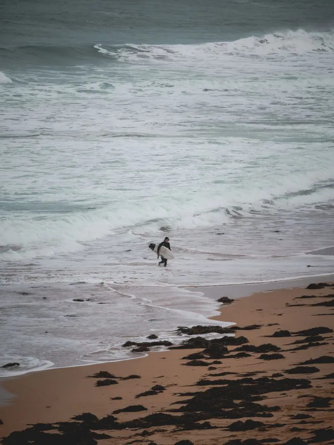 Surfers on the waves at a rugged coastal beach