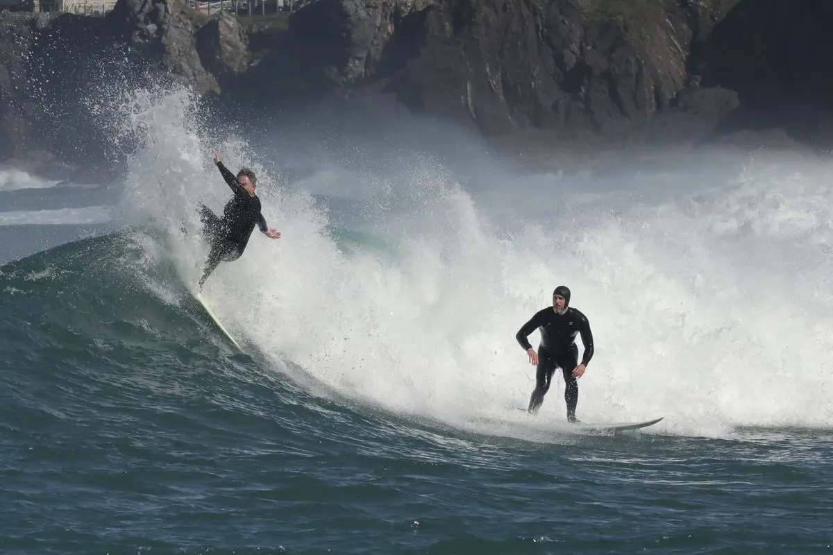 A surfer riding a large wave with spray behind
