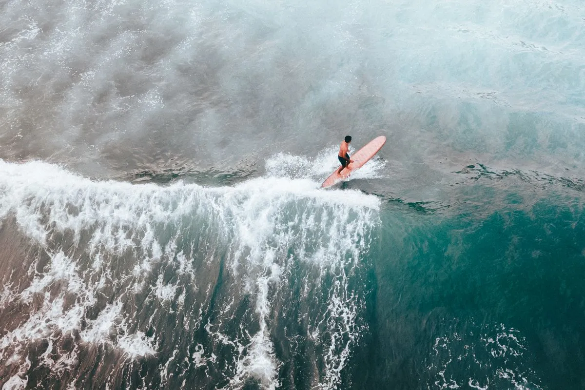 A surfer riding a wave seen from above