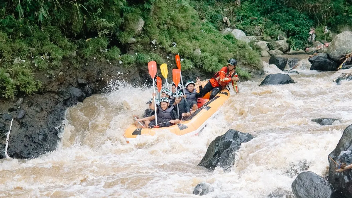 Group of adults white water rafting on a turbulent river.